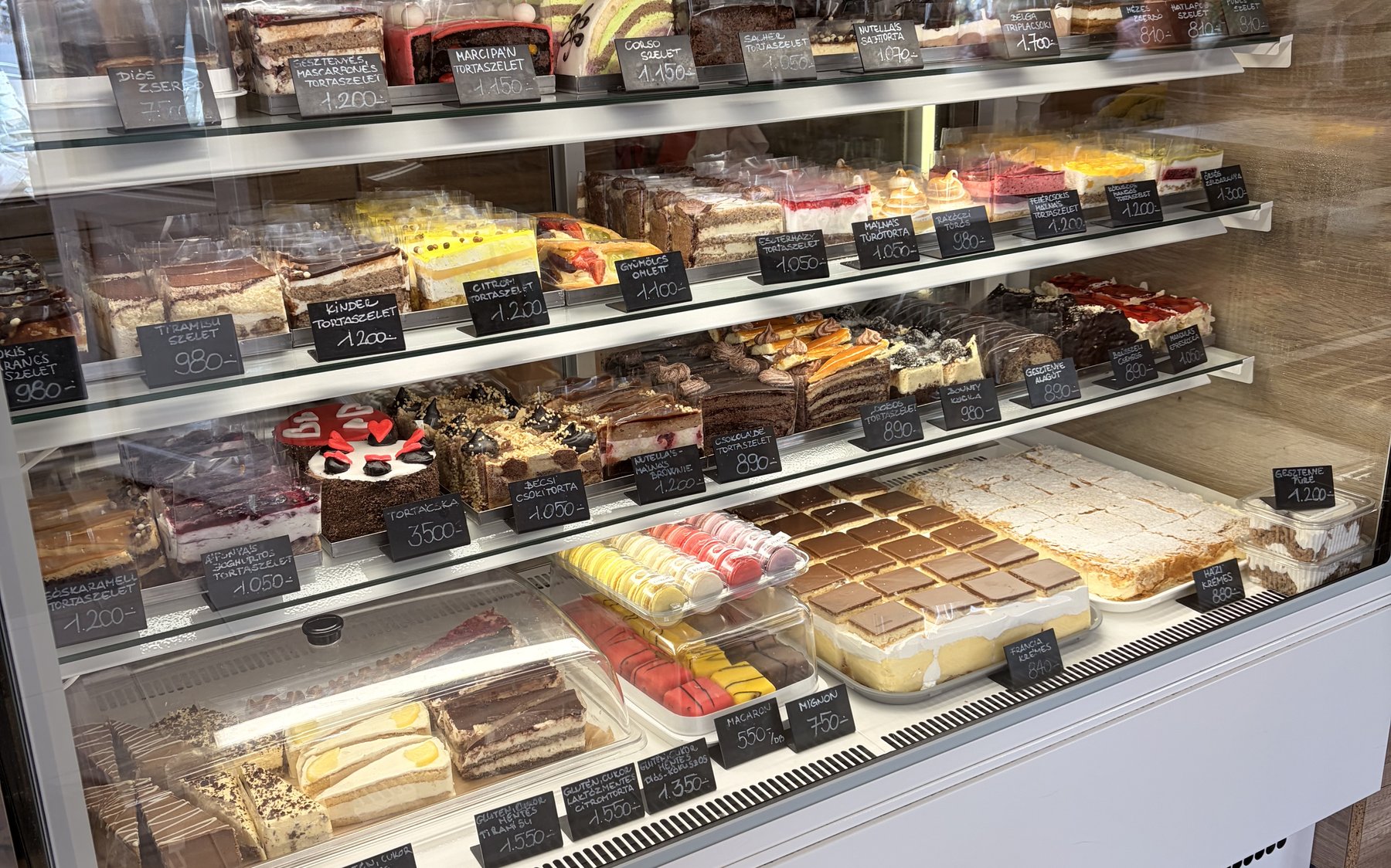 A cukrászda vitrinje sokféle friss tortaszelettel és süteménnyel